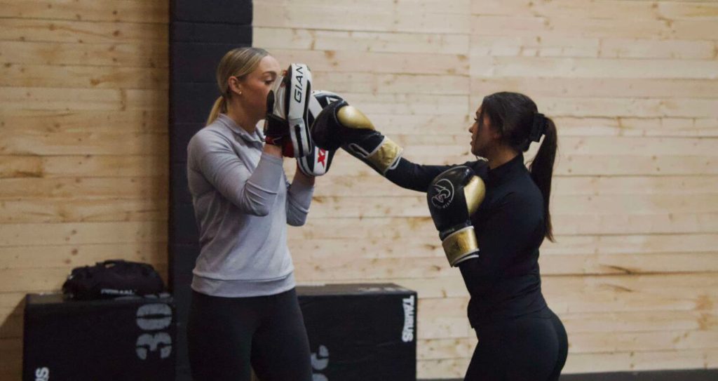 Friendly personal trainer chatting with client in private gym