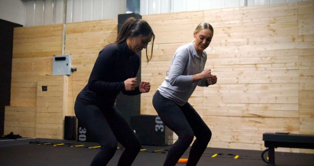Female client boxing with personal trainer in fitness studio